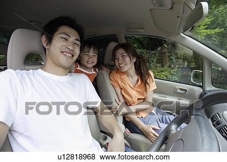 Stock Photo - A couple in a car with their daughter. Fotosearch