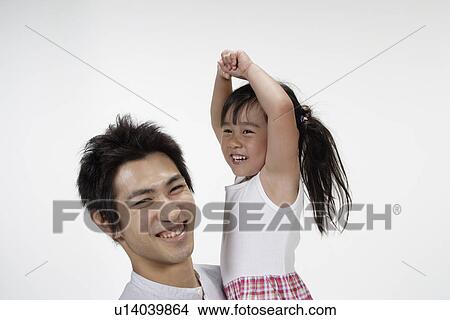 Picture - A young father lifting his daughter up in air. Fotosearch