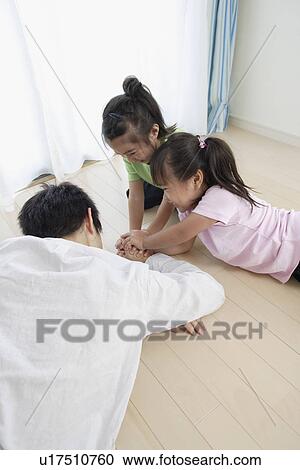 Stock Image - A young father playing with daughters. Fotosearch