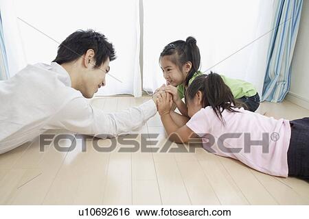 Stock Photograph - A young father playing with daughters. Fotosearch