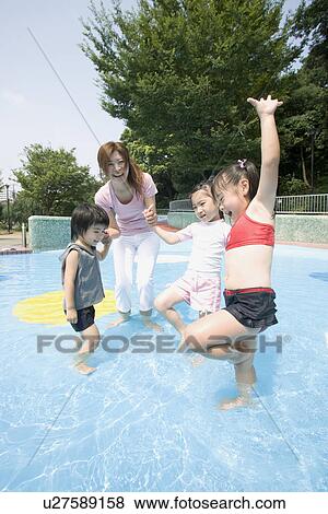 Stock Photo - Children playing in pool with mother. Fotosearch