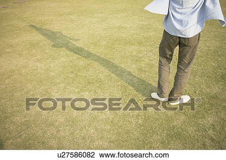 Stock Image - Legs of a man seen standing on the ground. Fotosearch