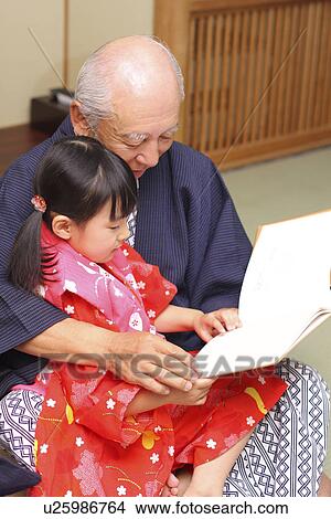 Picture - Girl in Yukata reading a book with grandfather. Fotosearch