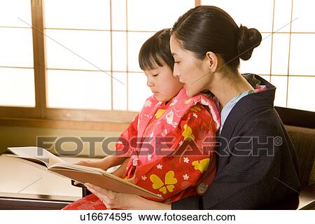 Stock Photography - Girl in Yukata reading a book with mother. Fotosearch