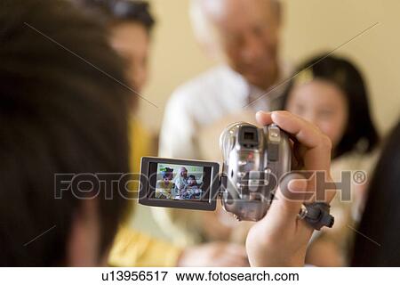Stock Photo - Man filming his family, differential focus. Fotosearch
