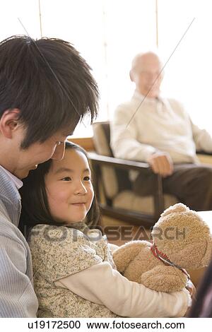 Stock Image - Multi-generation family in the inn, girl holding a teddy bear, differential focus. Fotosearch