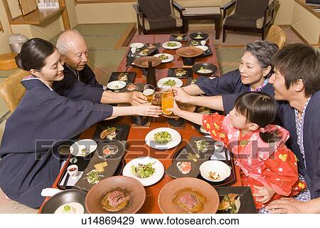 Stock Photo - Multi-generation family in Yukata having dinner, toasting with glasses. Fotosearch