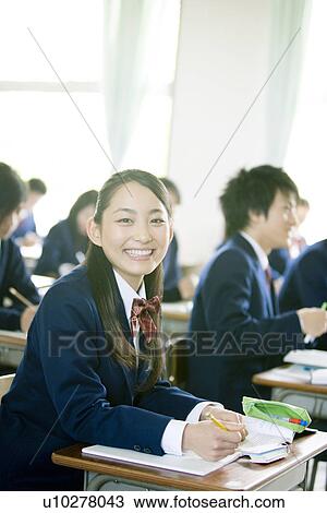 Stock Image - Portrait of a girl in classroom, smiling and looking at camera. Fotosearch