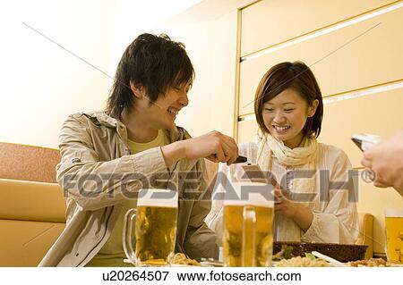 Stock Photo - Couple exchanging info on their cell phone. Fotosearch