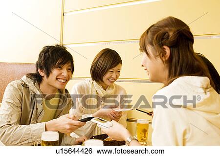 Stock Photograph - Group of young people exchanging info on cell phone. Fotosearch