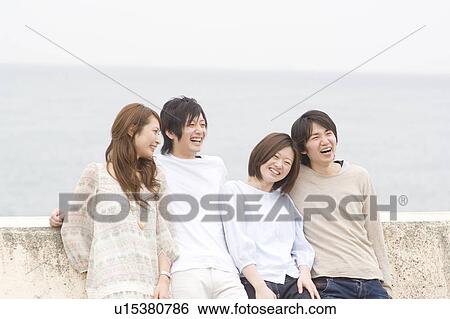 Stock Photograph - Group of young people leaning on breakwater. Fotosearch