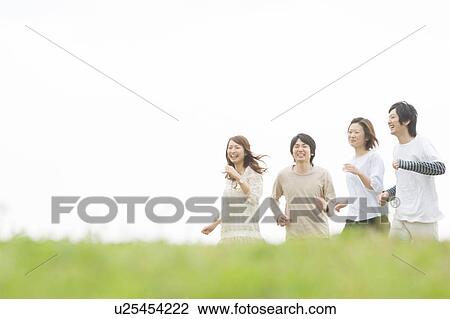 Stock Image - Group of young people running on grass. Fotosearch