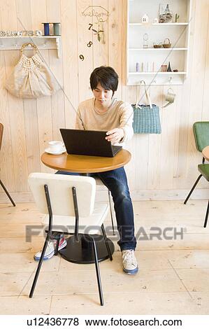 Stock Photo - Young man using laptop at a cafe. Fotosearch