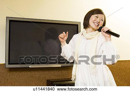 Young woman singing karaoke View Large Photo Image Stock Image - Young woman singing karaoke. Fotosearch