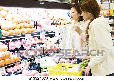 Stock Image - Young women grocery shopping. Fotosearch