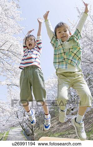 Picture - Boys Jumping Under Cherry Blossoms. Fotosearch