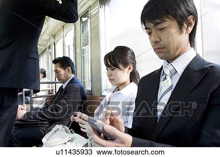Stock Image - Businessman using PDA on the train, sitting on the seat. Fotosearch