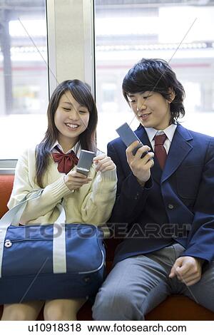 Girl and boy on the train, holding mobile phones on the seat, smiling View Large Photo Image Stock Photo - Girl and boy on the train, holding mobile phones on the seat, smiling. Fotosearch