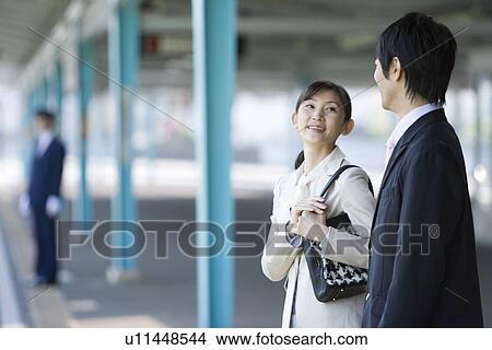 Man and woman waiting for the train at platform, smiling, differential focus View Large Photo Image Picture - Man and woman waiting for the train at platform, smiling, differential focus. Fotosearch