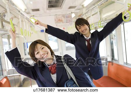 Stock Photo - Portrait of high school students on the train, hanging on to straps, smiling. Fotosearch