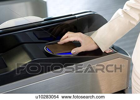 Picture - Woman walking through automatic ticket wicket at station, close up. Fotosearch