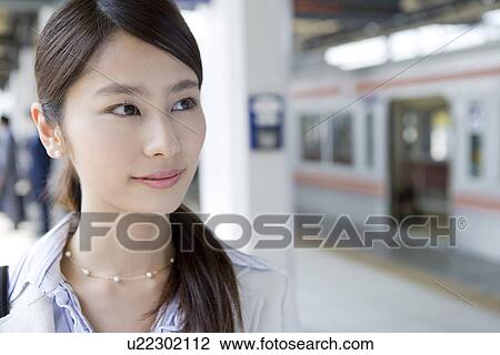 Stock Image - Young woman at platform, smiling, close up. Fotosearch