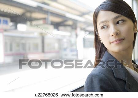 Stock Photograph - Young woman looking outside from the window, looking back. Fotosearch