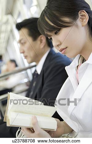 Stock Photo - Young woman reading a book on the train. Fotosearch
