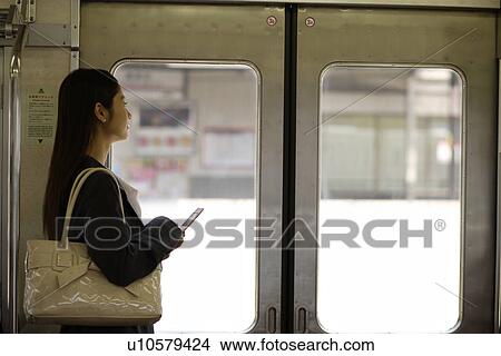 Young woman standing beside the door on the train View Large Photo Image Picture - Young woman standing beside the door on the train. Fotosearch