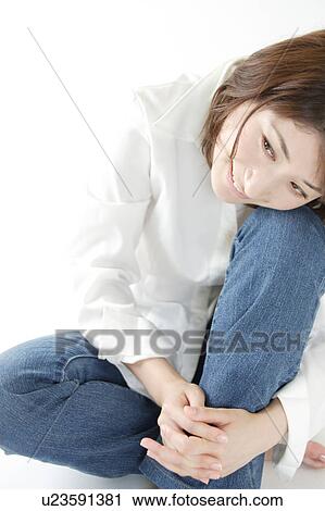 Stock Image - A young woman hugging her knee. Fotosearch