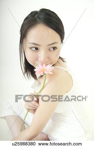Stock Image - A young woman kissing to a flower. Fotosearch
