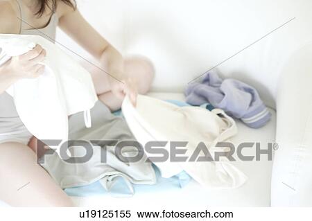 A young woman folding laundry View Large Photo Image Stock Photography - A young woman folding laundry. Fotosearch