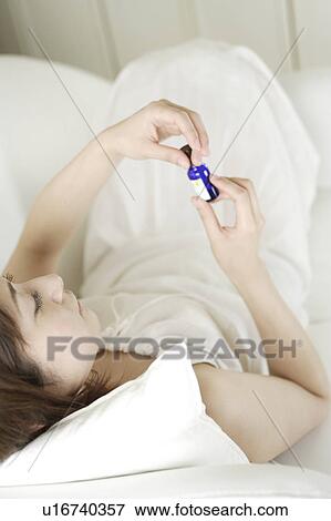 Stock Photo - A young woman holding aromatherapy oil. Fotosearch