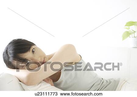Stock Image - A young woman lying on a sofa. Fotosearch