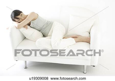 Stock Photo - A young woman lying on a sofa. Fotosearch