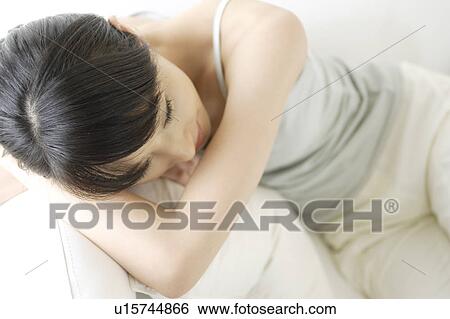 Stock Photograph - A young woman lying on a sofa. Fotosearch