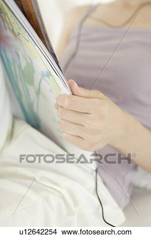 Picture - A young woman reading a magazine. Fotosearch
