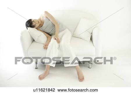 Stock Image - A young woman sitting on a sofa. Fotosearch