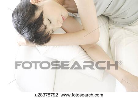 Stock Image - A young woman sleeping on a sofa. Fotosearch