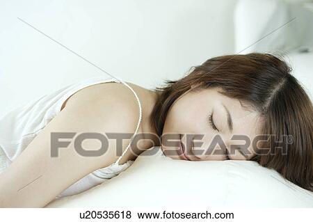 Stock Photo - A young woman sleeping on a sofa. Fotosearch
