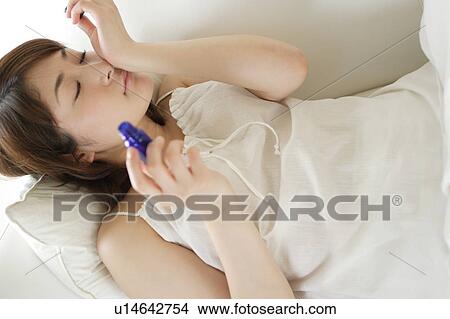Picture - A young woman smelling aromatherapy oil. Fotosearch
