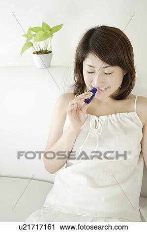 Stock Image - A young woman smelling aromatherapy oil. Fotosearch