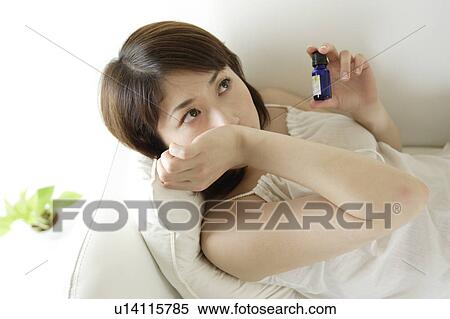 Stock Photography - A young woman smelling aromatherapy oil. Fotosearch