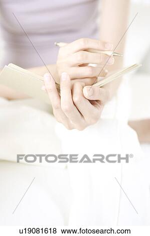 Stock Photo - A young woman taking a memo. Fotosearch