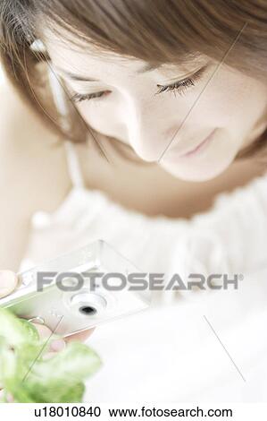 Stock Image - A young woman taking a picture. Fotosearch