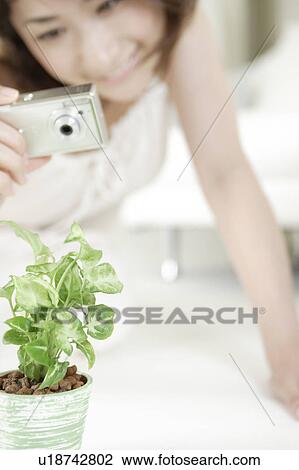 Stock Image - A young woman taking a picture. Fotosearch