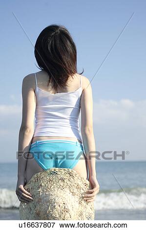 A young woman holding a hat in beach, rear view View Large Photo Image Stock Photo - A young woman holding a hat in beach, rear view. Fotosearch