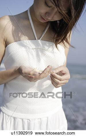 A young woman holding a shell View Large Photo Image Stock Photo - A young woman holding a shell. Fotosearch