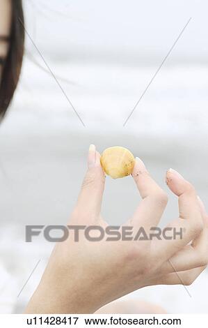 Stock Photo - A young woman holding a shell. Fotosearch