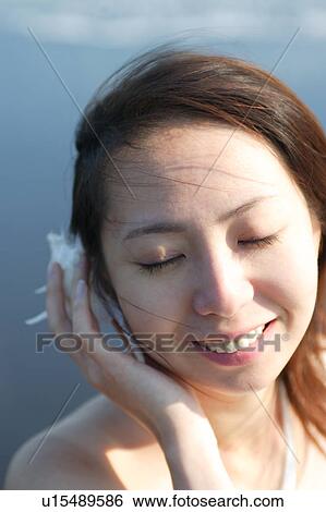 A young woman listening a shell View Large Photo Image Stock Photograph - A young woman listening a shell. Fotosearch